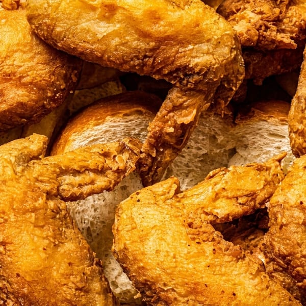Close-up of golden-brown fried chicken wings and white bread slices in a basket.